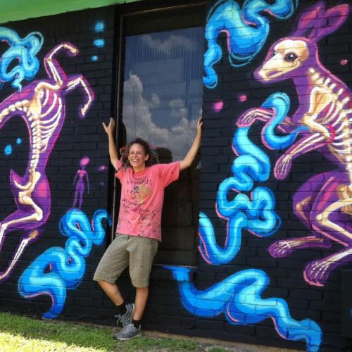 Staff Member Posing next to Painted Murals outside Jerry's Artarama Art Supply Store in Austin, TX