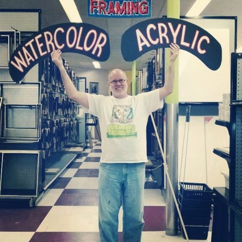 A Staff Member with Watercolor & Acrylic Paint Signs at Jerry's Artarama Art Supply Store in Nashville, TN