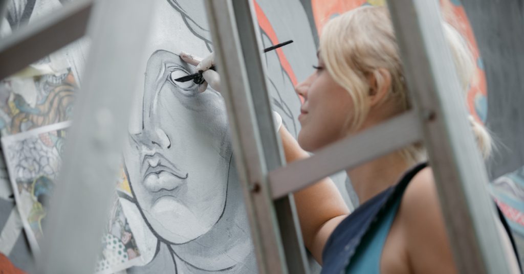 woman drawing an eye on a gray painting